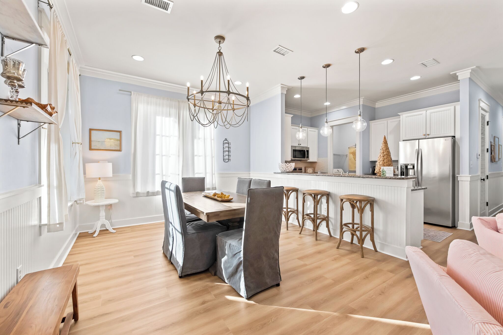 A modern kitchen with white cabinets, a stainless steel refrigerator, and a central island with bar stools.