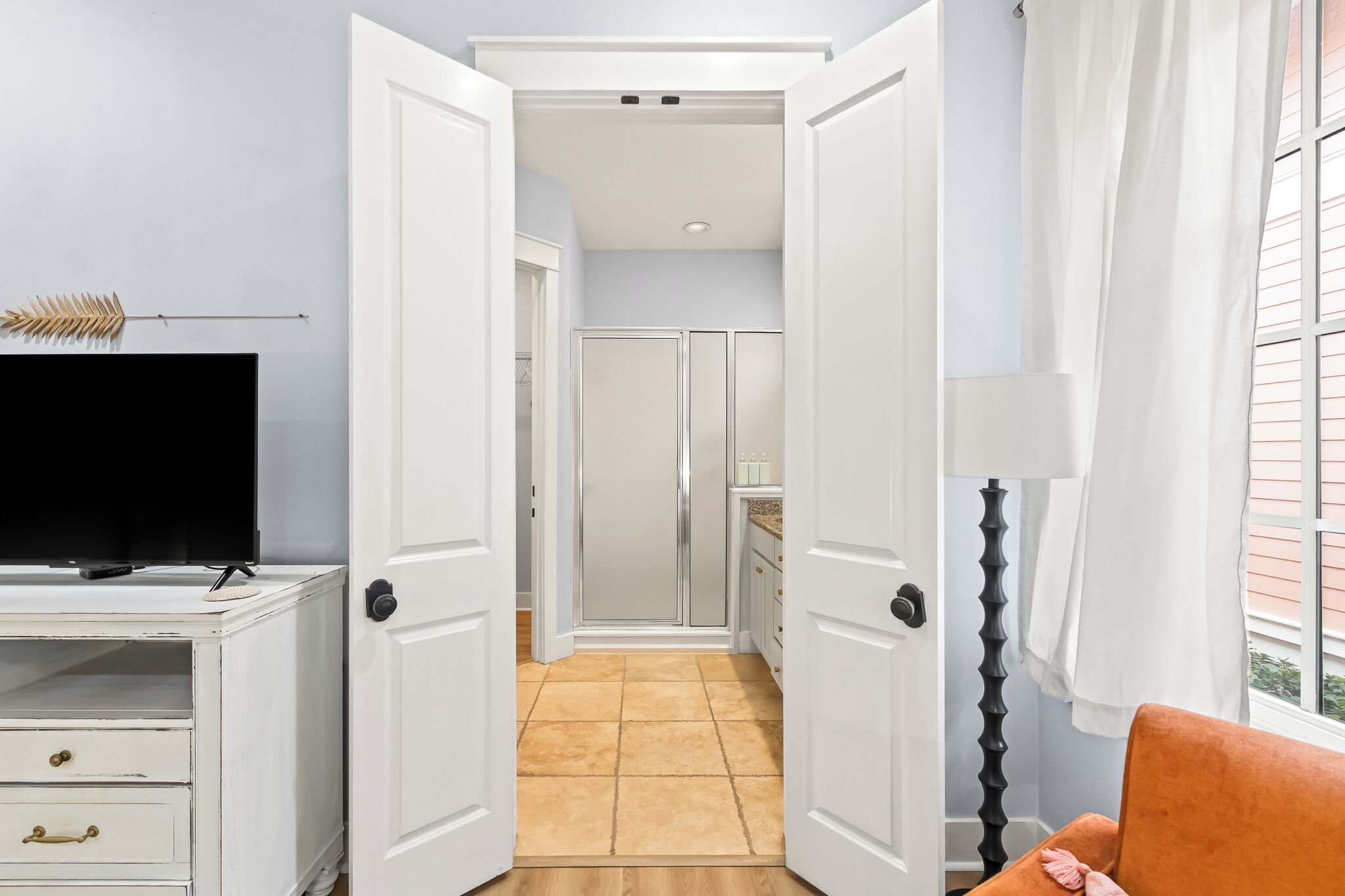 A hallway with white doors leading to a kitchen area.