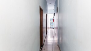 A narrow hallway with light blue walls and a tiled floor, leading to a door at the end.