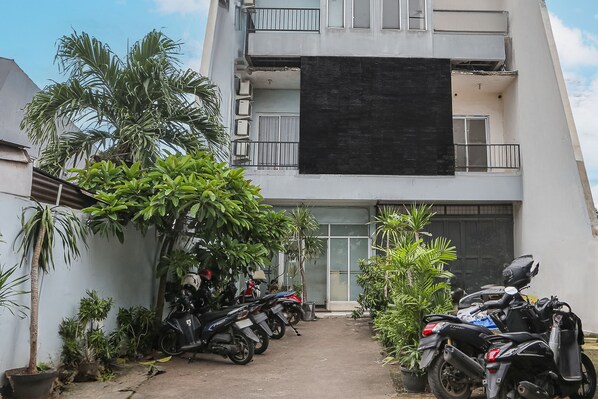 A building with a black banner, potted plants, and parked motorcycles. - OYO 93584 RukotelNearICE BSD (Tangerang)