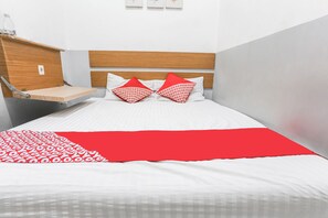 A hotel room with a bed, a wooden headboard, a small wooden shelf, and a red and white patterned throw blanket. - OYO 93584 RukotelNearICE BSD (Tangerang)