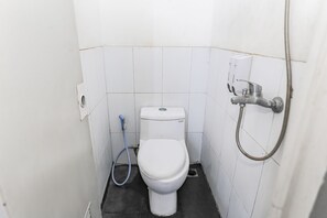 A small, white-walled bathroom with a toilet, a blue hose, and a showerhead. - OYO 93584 RukotelNearICE BSD (Tangerang)