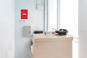 A reception desk with a 'Reserved' sign, a 'Distance' sign, and a red 'OYO' sign on the wall. - OYO 93584 RukotelNearICE BSD (Tangerang)