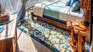 A bedroom with a large window, a bed, a wooden side table, and a patterned rug. - Traverse City - Luxury on the Edge - 10 (Williamsburg)