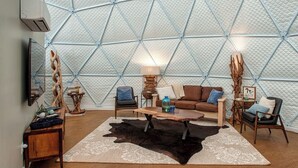 A cozy living room with a geometric patterned wall, a wooden coffee table, a brown sofa, and a black leather chair. - Traverse City - Luxury on the Edge - 10 (Williamsburg)