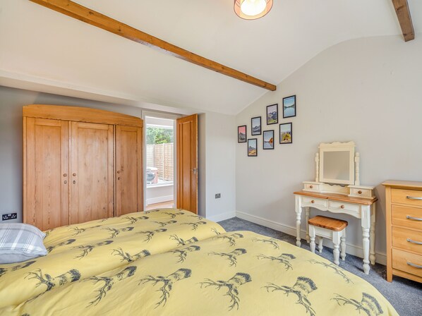 A bedroom with a bed, wooden wardrobe, dresser, and a door leading to a balcony.
