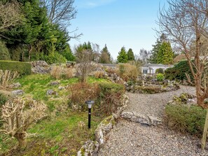 A garden with a gravel path, various shrubs, and a building with a white facade.