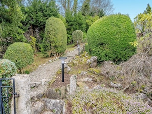 A garden with neatly trimmed hedges, a gravel path, and a metal gate.