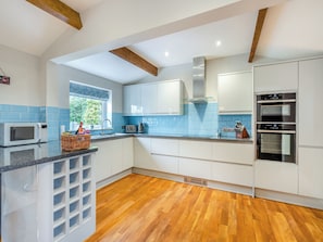 A modern kitchen with white cabinets, a microwave, a toaster, and a double oven.