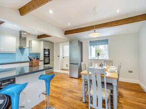 Una cocina moderna con comedor, que presenta techo de madera, horno empotrado y mesa de comedor con sillas.