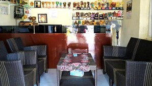 A restaurant with wicker furniture, a counter with various trophies, and a clock on the wall. - Hotel O Wisma Air Mancur Homestay Syariah (Tumpang)