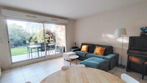 A spacious living room with a large sliding glass door leading to a patio, a sofa with cushions, a small round table, and a piano.