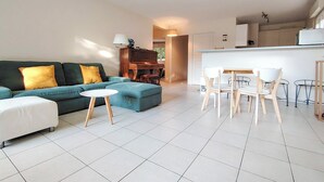 A modern living room with a sofa, a small round table, and a dining area with chairs.