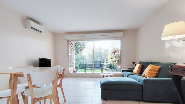A modern living room with a dining area, a sofa, and a TV.