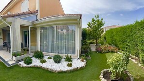 A modern house with a glass conservatory, a well-maintained lawn, and a variety of plants. - NEW ! VILLA with Parking, Collective Pools, Garden and AC - BENAKEY (Cannes)
