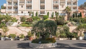 Un hôtel à plusieurs étages, doté d’une façade symétrique, de balcons et d’un jardin paysager à l’avant.