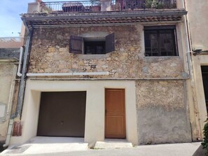 Un edificio a due piani con facciata in pietra, una porta in legno e un garage.