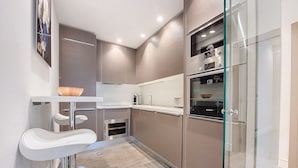 A modern kitchen with a built-in oven, a glass-fronted refrigerator, and a white countertop. - N&J - VICTOIRE - Central - Near Beach (Niza)