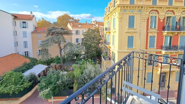 Un immeuble à plusieurs étages doté de balcons, d’un toit recouvert de tuiles rouges et d’un espace jardin.