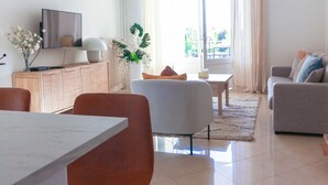 A modern living room with a flat-screen TV, a dining table, and comfortable seating. - Beautiful Renovated Studio with AC and TERRACE - Benakey (Cannes)