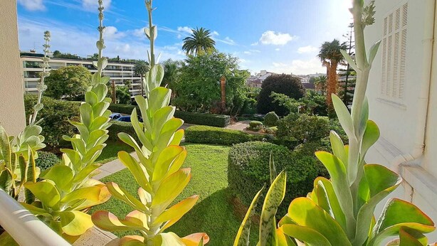A view from a balcony overlooking a well-maintained garden with various plants and a clear blue sky. - Beautiful Renovated Studio with AC and TERRACE - Benakey (Cannes)