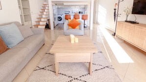A modern living room with a sofa, coffee table, and a kitchen in the background. - Beautiful Renovated Studio with AC and TERRACE - Benakey (Cannes)