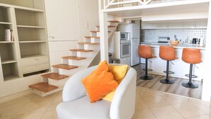 A modern kitchen with white cabinets, a microwave, and a sink. There is a staircase with wooden steps leading to a loft area. - Beautiful Renovated Studio with AC and TERRACE - Benakey (Cannes)