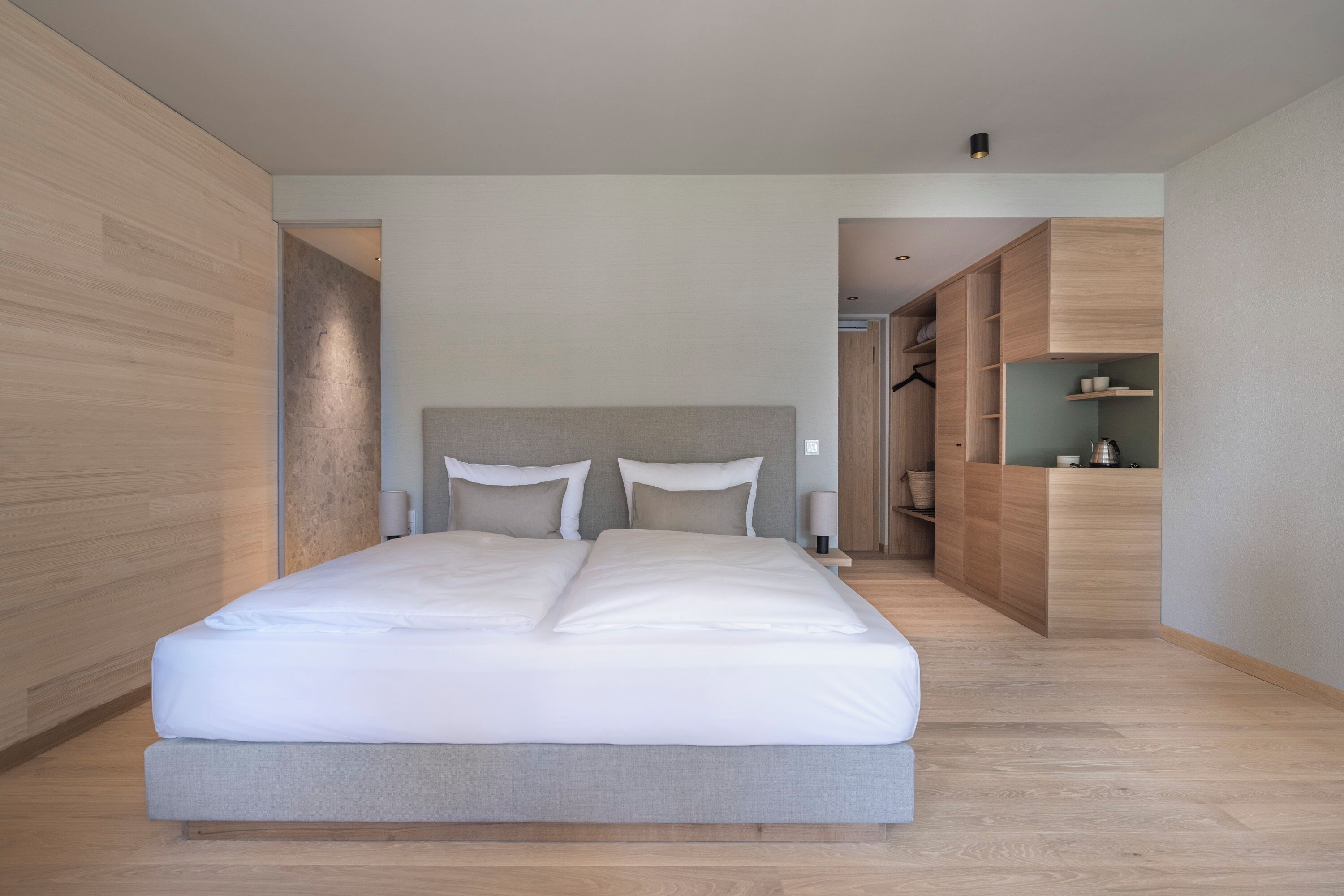 Quarto moderno com cama grande, soalho de madeira e armários embutidos.