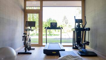 Un gimnasio en casa con cinta de correr, elíptica, bicicleta estática y pelota de ejercicios.