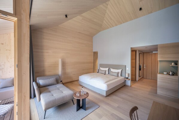 A modern hotel room with a large bed, a sofa, a small table, and a wooden ceiling. - Seegut Zeppelin – a member of Design Hotels (Friedrichshafen)