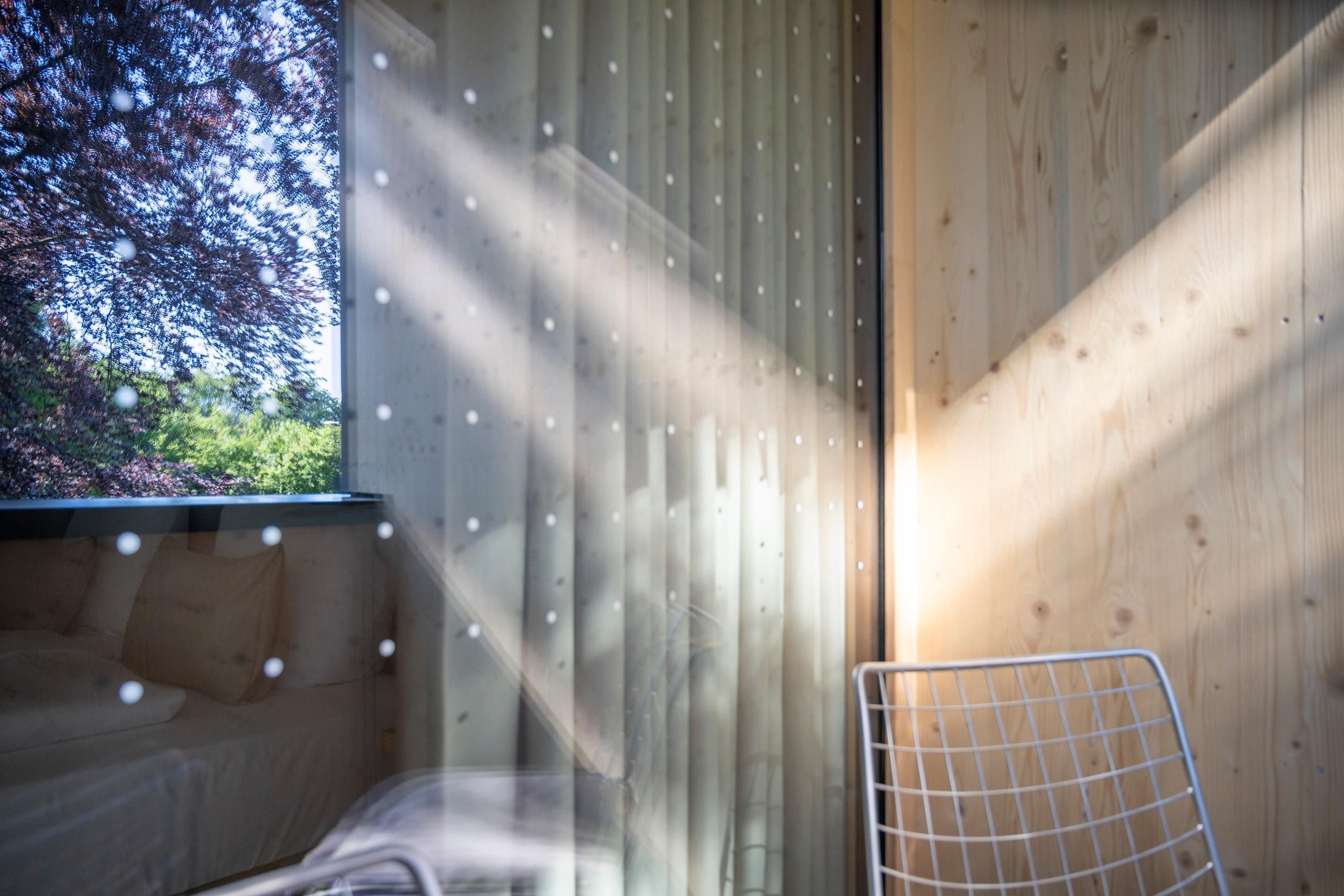 A room with a bed, a chair, and a window with a view of trees.