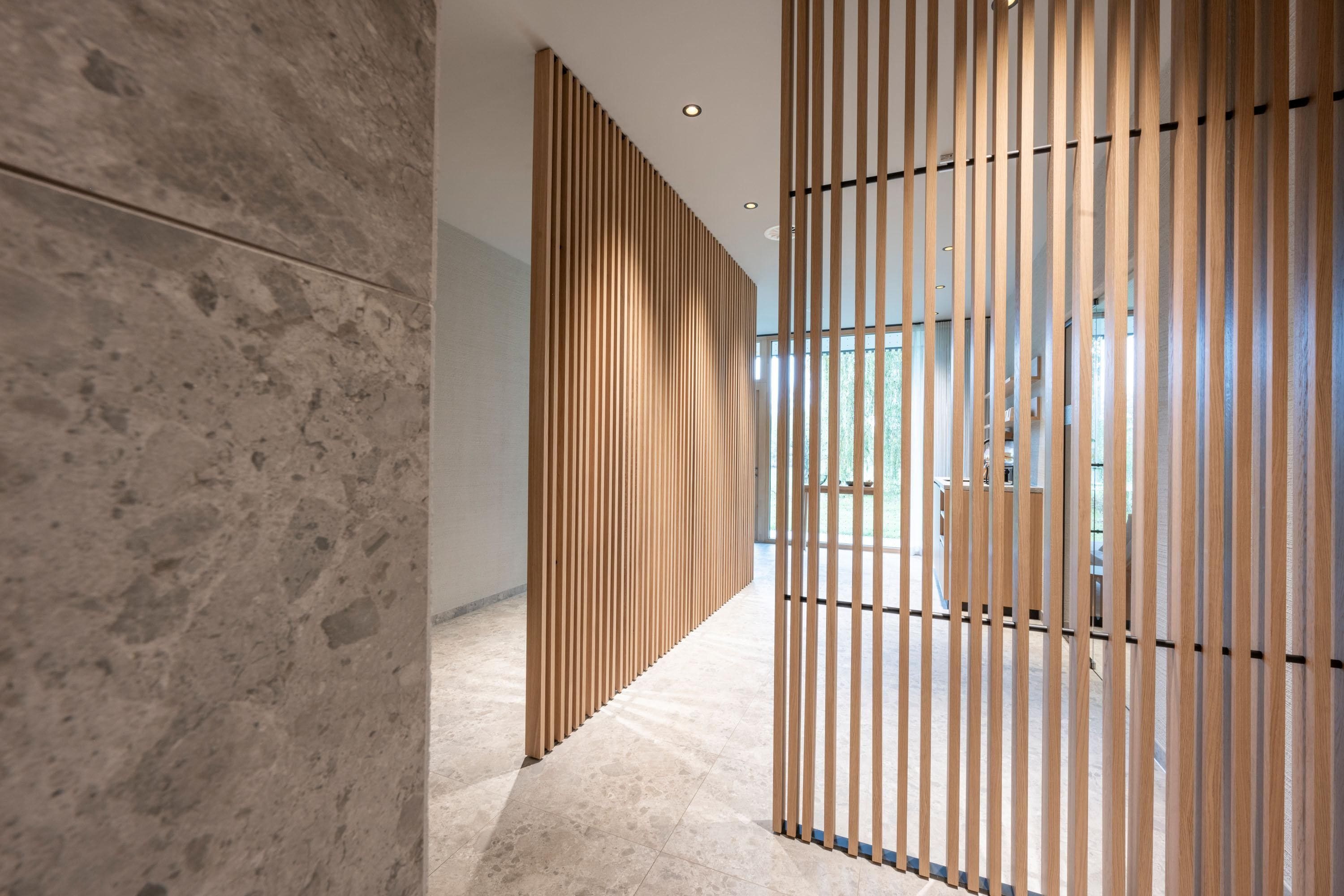 Ein Korridor mit modernem Design, der eine Holzlamellen-Trennwand und eine Steinwand zeigt.