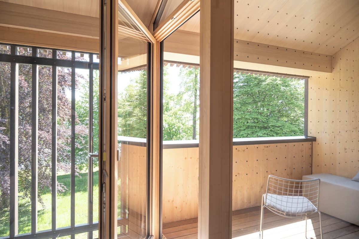 A modern interior with large windows, a wooden ceiling, and a white chair.