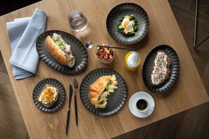 A wooden table with various dishes, including sandwiches, a salad, and a cup of coffee. - Seegut Zeppelin – a member of Design Hotels (Friedrichshafen)