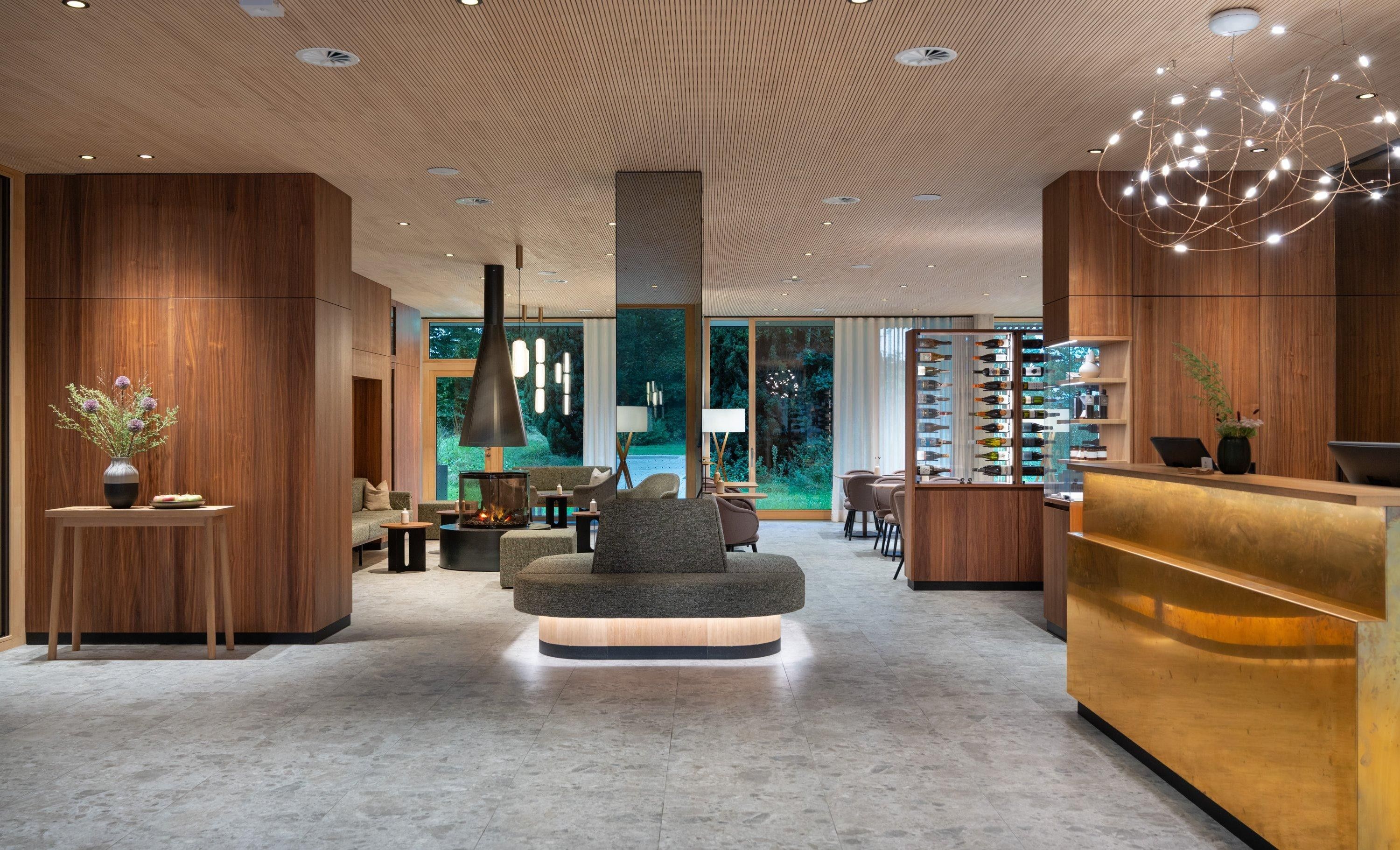 Eine moderne Hotelhalle mit einer zentralen Sitzecke, einer Rezeption und einer Weinauslage.