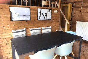 Cozy room with a dining table, two chairs, and a wooden staircase.