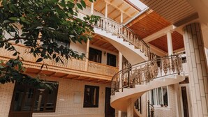 Un interior de varios niveles con una escalera de caracol, paredes de ladrillo y vigas de madera.