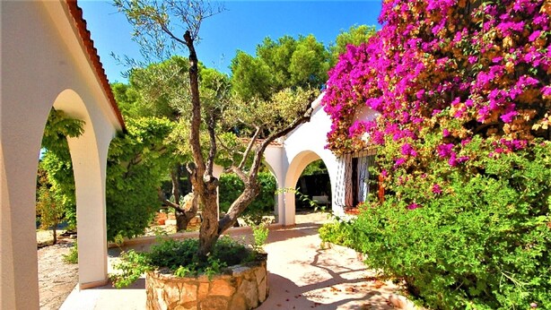 A courtyard with white arches, a stone planter, and vibrant pink bougainvillea. - SAONA VILLAS (CP DOLORES) : villa 10 personnes, piscine privée, climatisation (Tres Calas)