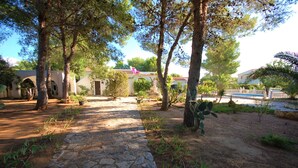A courtyard with stone pathways, trees, and a fountain. - SAONA VILLAS (CP DOLORES) : villa 10 personnes, piscine privée, climatisation (Tres Calas)