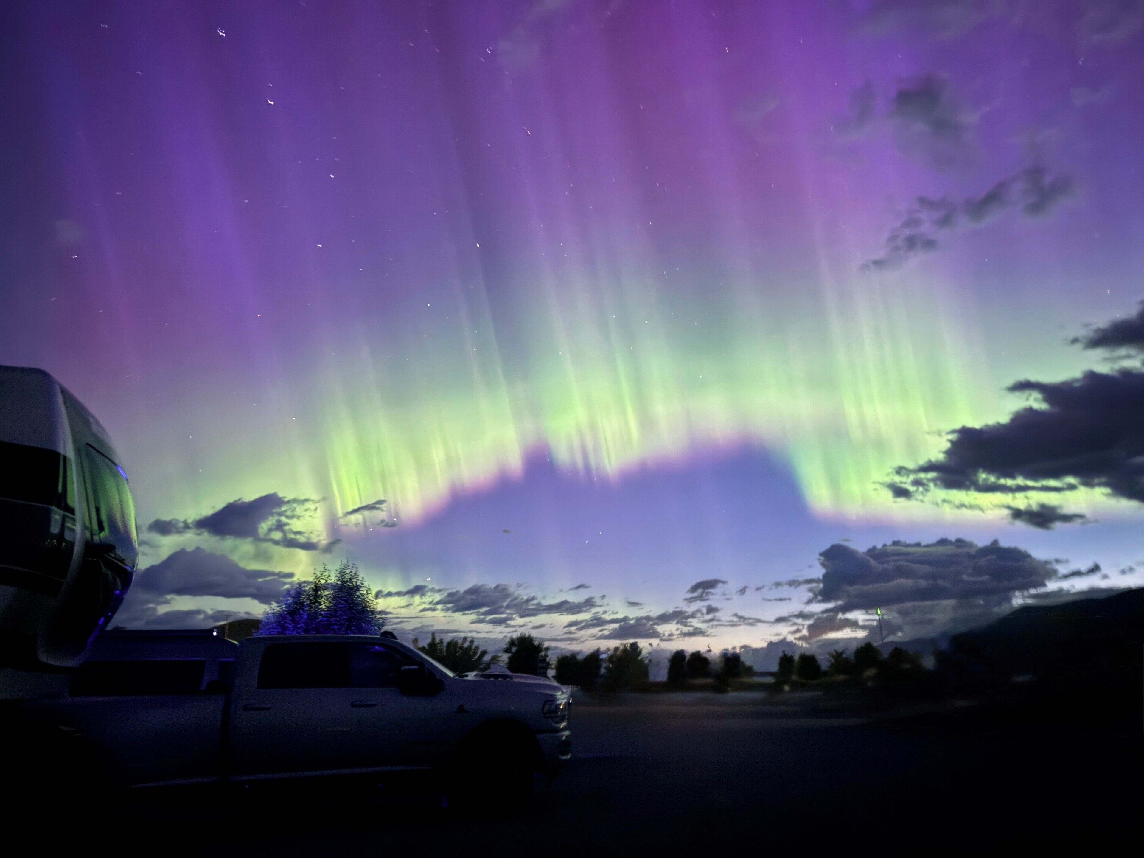 A vehicle parked in a parking lot with a view of the aurora borealis in the background.