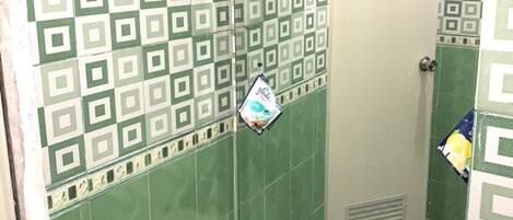 A bathroom with green patterned tiles, a toilet, and a shower area.