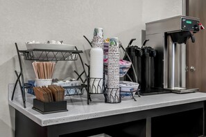 A buffet setup with stacked plates, bowls, and utensils on a counter. - Red Roof Inn Flint (Flint)