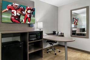 A modern hotel room with a flat-screen TV, a desk with a chair, a microwave, and a coffee maker. - Red Roof Inn Flint (Flint)