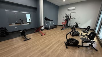 A gym with exercise equipment, a mirror, and a window.