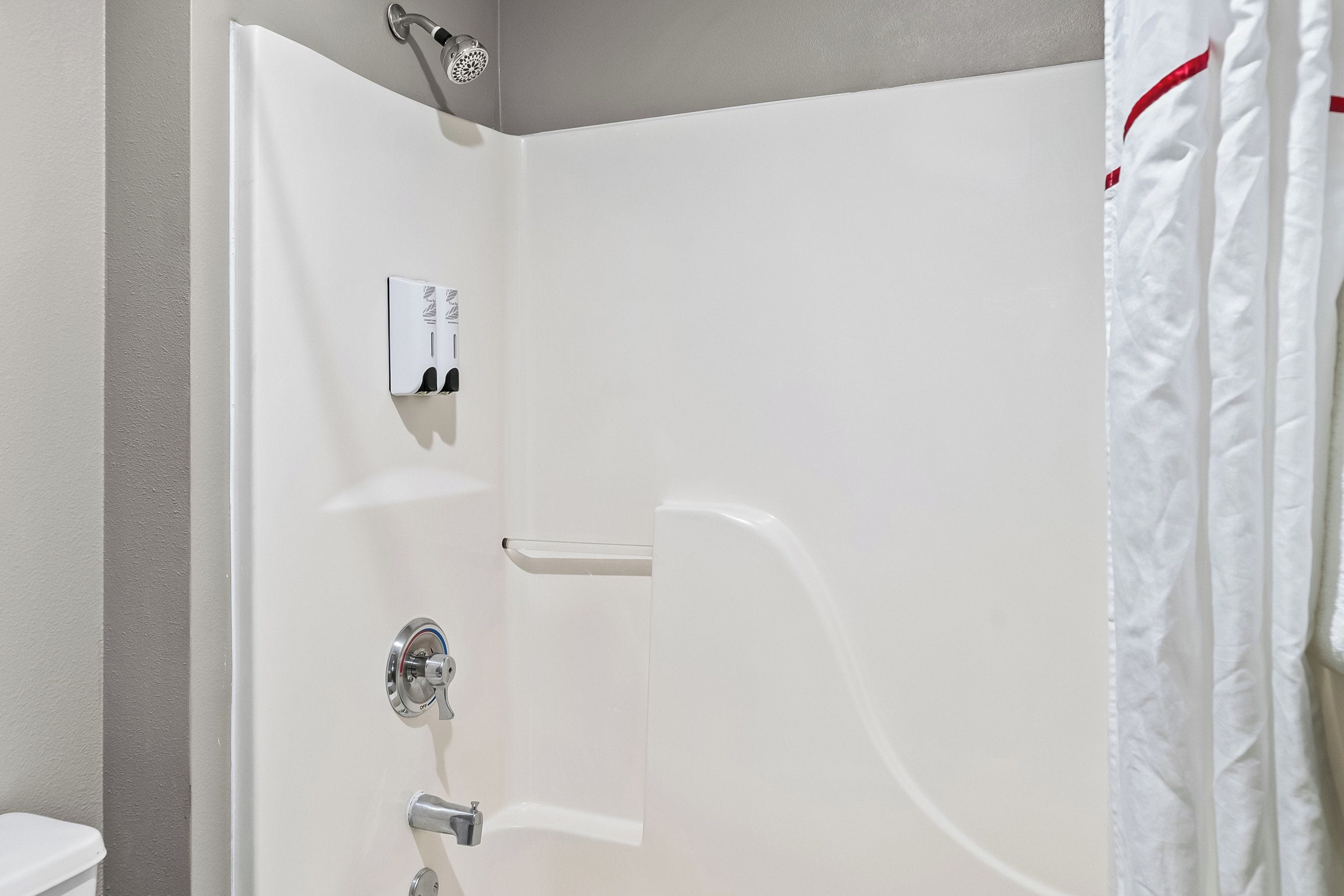 A white shower enclosure with a control panel, a towel rack, and a shower curtain.