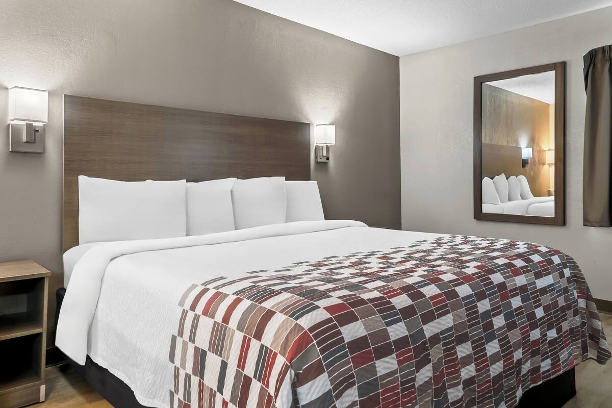 Ein Hotelzimmer mit einem großen Bett, einem Nachttisch und einem Spiegel an der Wand.