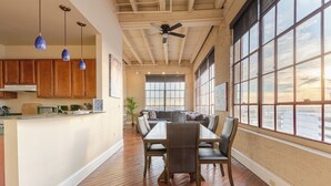 A spacious kitchen with wooden cabinets and a dining area with a large table and chairs. - Luxurious Downtown Condo w/ Panoramic City Views and Free Secure Onsite Parking. (New Orleans)