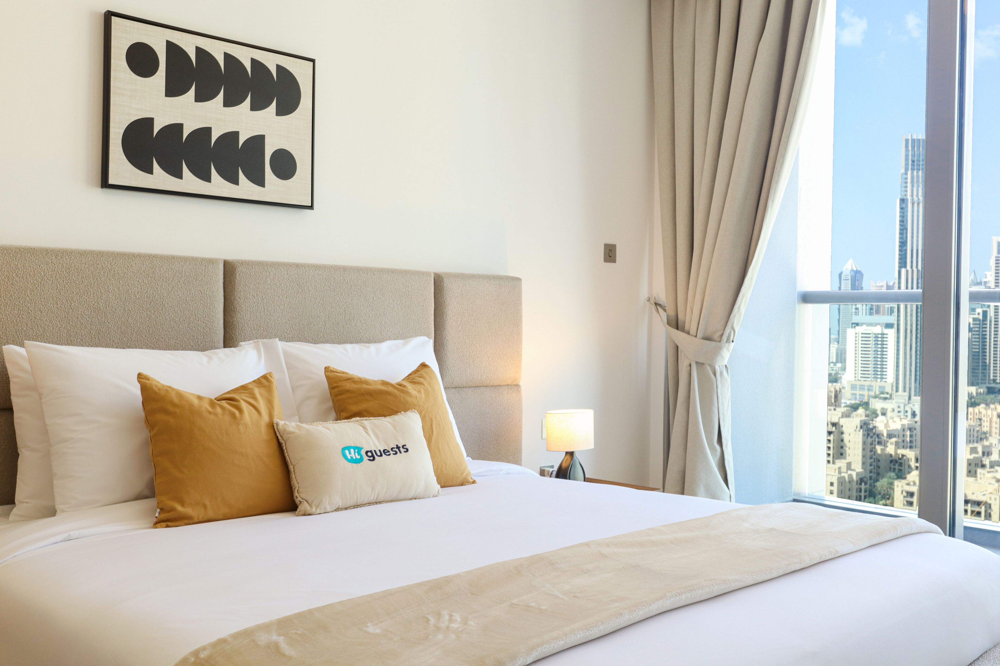 Une chambre d’hôtel avec un grand lit, une vue sur la ville et une œuvre d’art encadrée au mur.