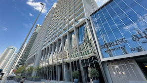 Un immeuble moderne de grande hauteur, doté d’une façade en verre réfléchissant, d’une grande enseigne indiquant « SINGAPORE » et surplombant un ciel bleu clair.