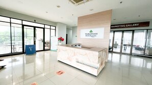 Un espace d’accueil doté d’un comptoir en marbre, d’une enseigne indiquant « TAMANSARI PANORAMIC » et d’une autre indiquant « GALERIE DE MARKETING ».
